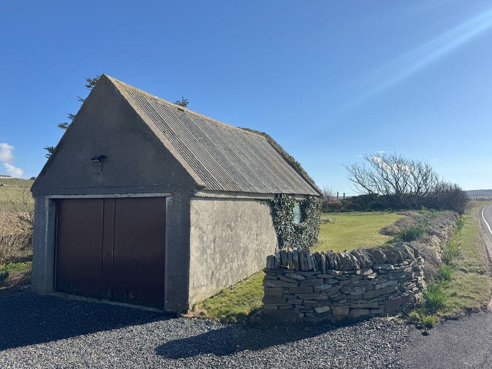 A garage beside a road with grass and stone wall at Withi-Gill