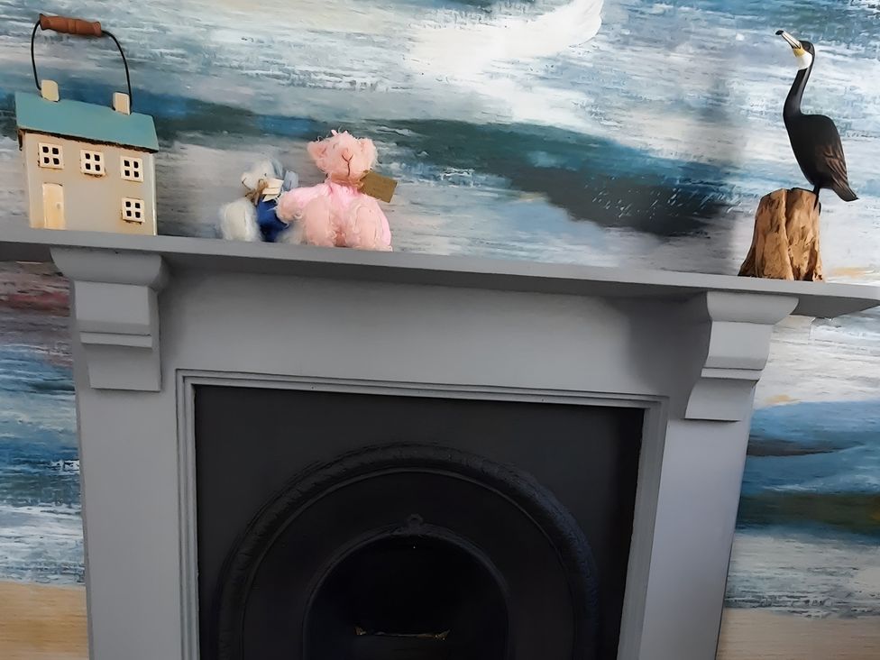 A mantle with a house decoration and plush toys at Lil Nauti