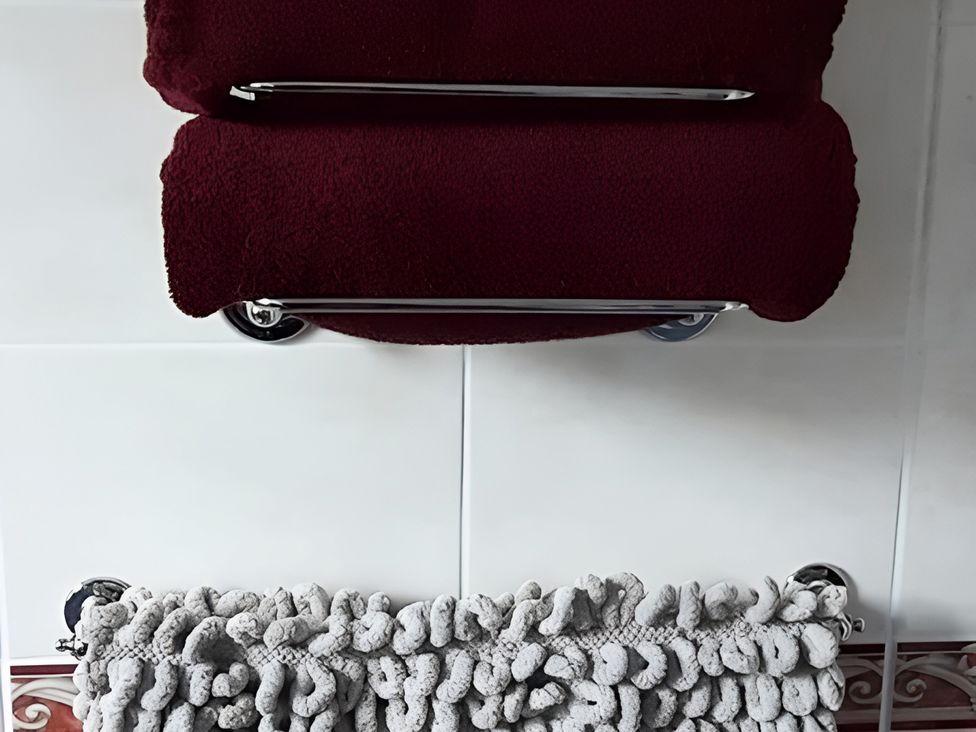 Red towels on a rack and a gray bath mat in a bathroom at Lil Nauti