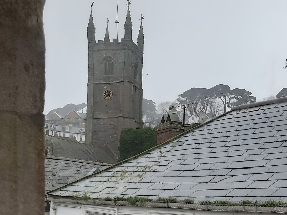 A church tower with a clock and surrounding roofs and trees at Lil Nauti
