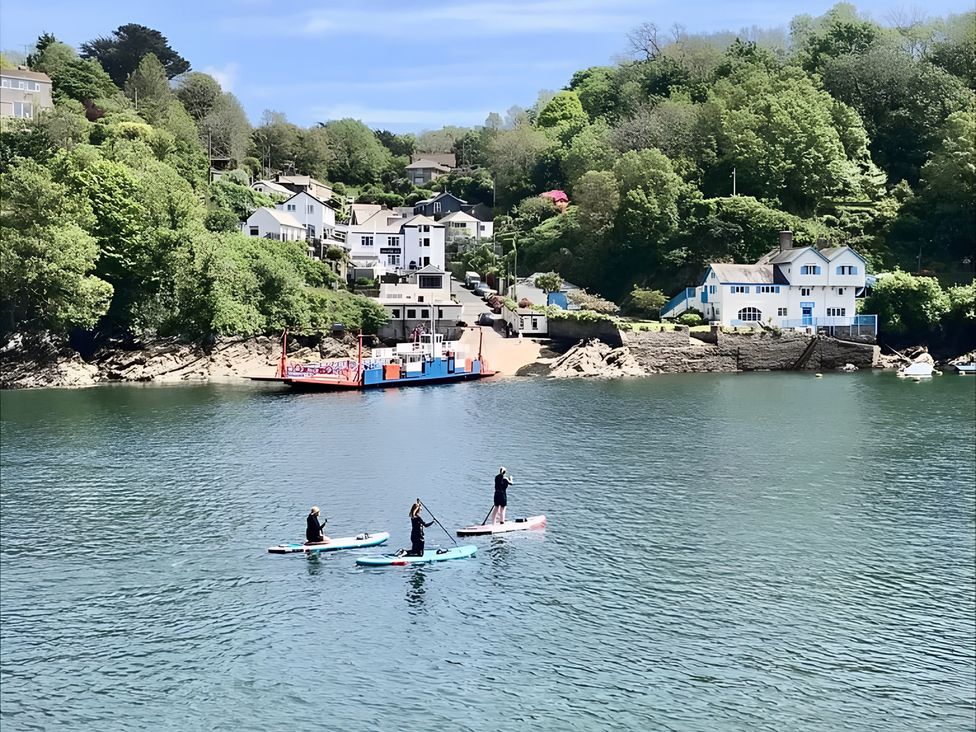 Paddle boarders on water with houses and trees in the background at Lil Nauti