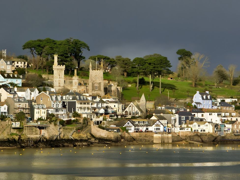 A coastal view with buildings and trees on a hill near the water at Lil Nauti