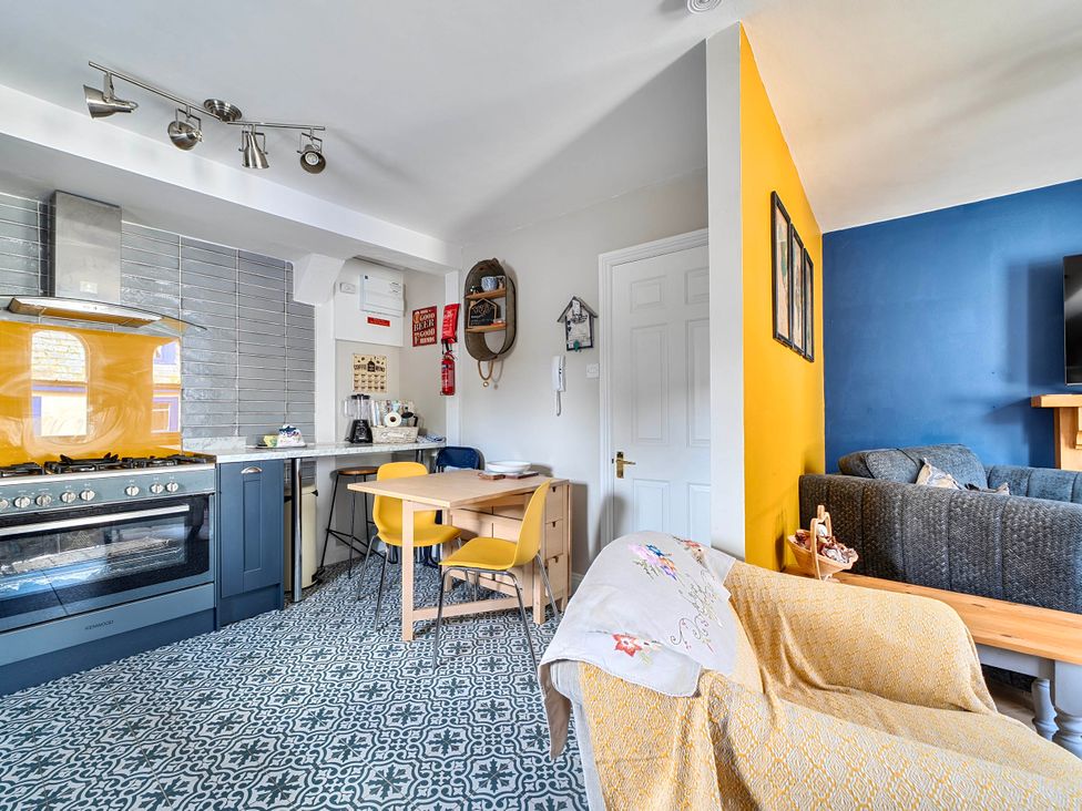 A kitchen and living area with a table and chairs at Lil Nauti in Fowey