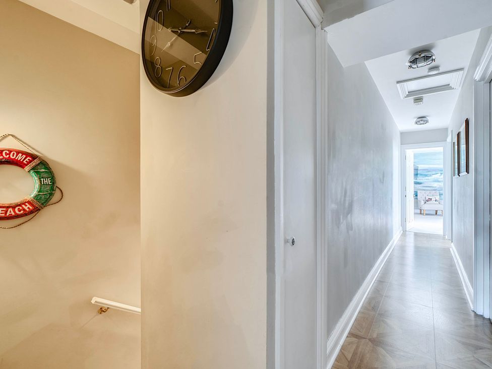 A hallway with a clock and life ring at Lil Nauti Fowey