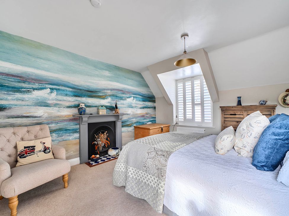 A bedroom with a bed and armchair at Lil Nauti in Fowey