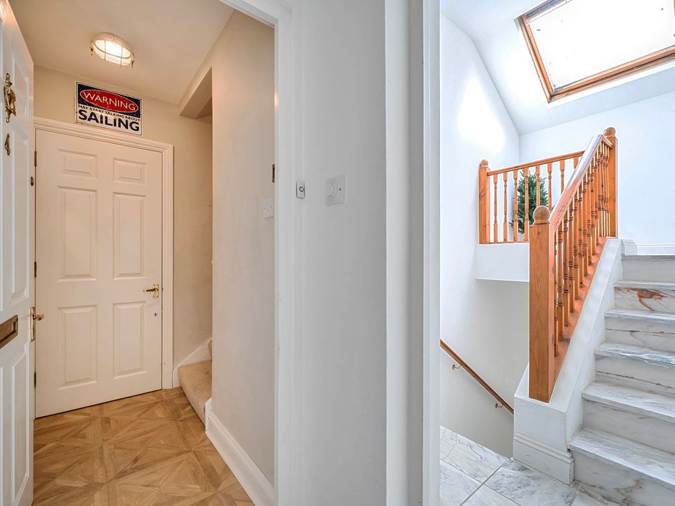 A hallway with a staircase and a door at Lil Nauti in Fowey