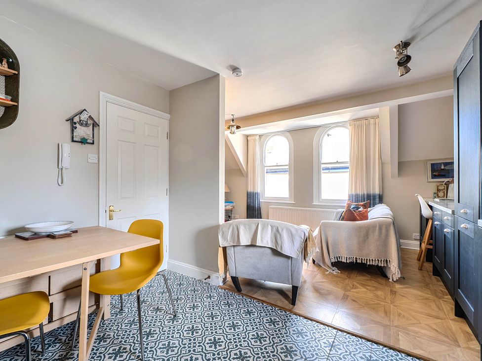 A living room with dining table and yellow chairs at Lil Nauti in Fowey