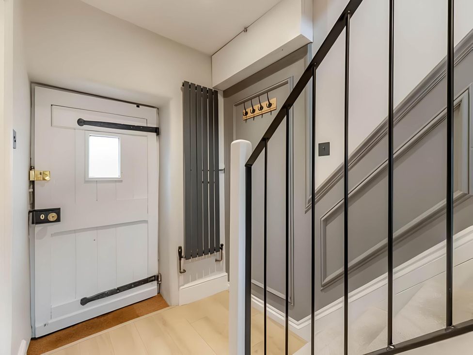 A hallway with a front door and staircase at Belmont Cottage in Matlock