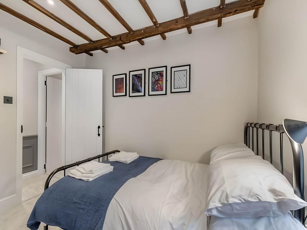 A bedroom with a bed and artwork on the wall at Belmont Cottage in Matlock