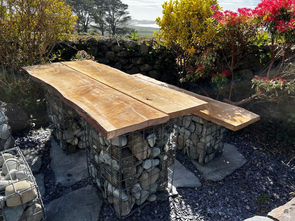 A wooden table supported by stone structures in a garden at Bwthyn Nain 