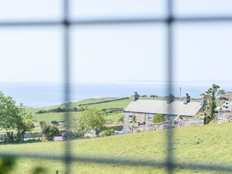 A view of houses and sea from the window at Bwthyn Nain in Harlech