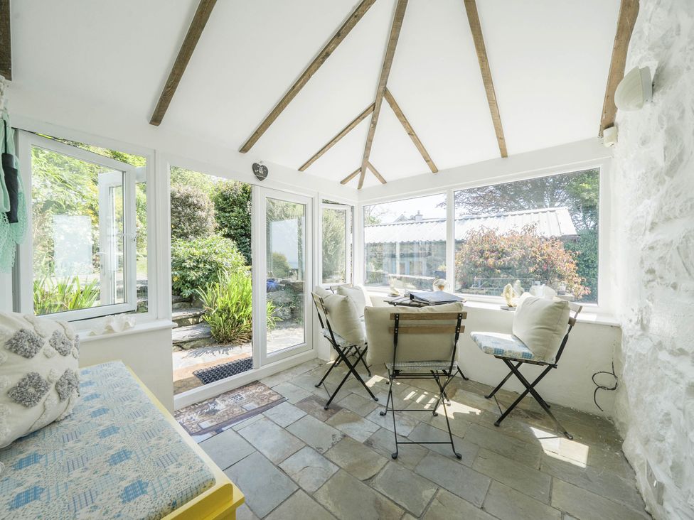 A conservatory with a table and chairs at Bwthyn Nain in Harlech