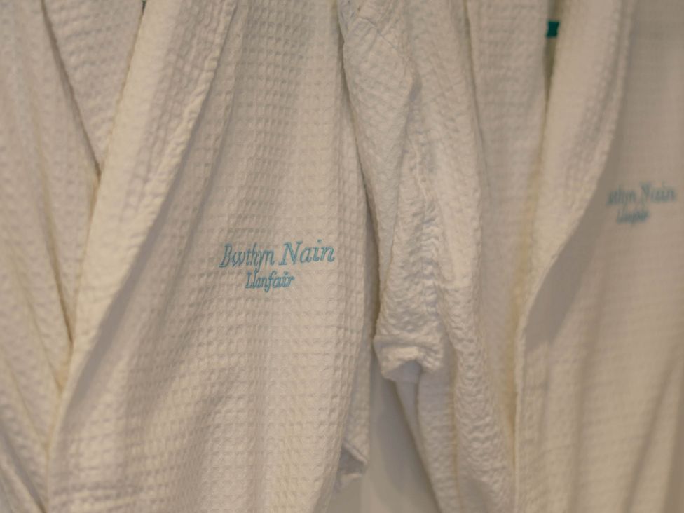 Bathrobes hanging with Bwthyn Nain embroidery in a bathroom