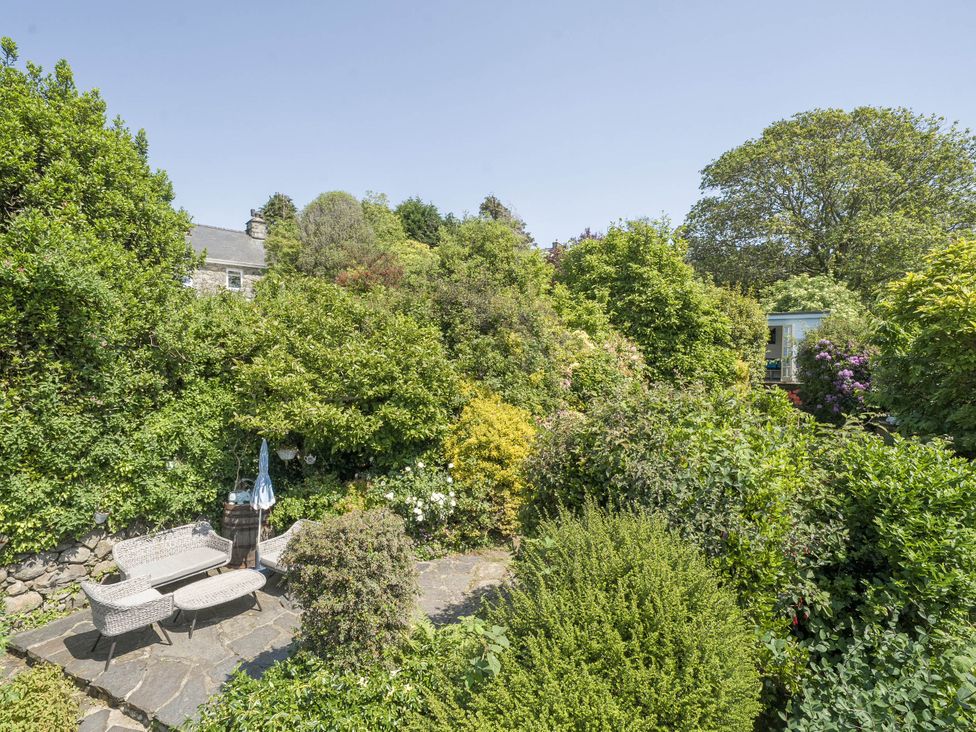 A garden with a sofa, table, and plants at Bwthyn Nain in Harlech