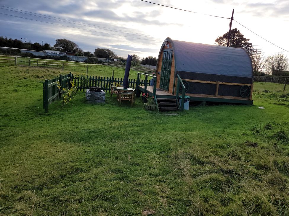 A hut with a wooden deck and fence in an outdoor area at St Austell Glamping