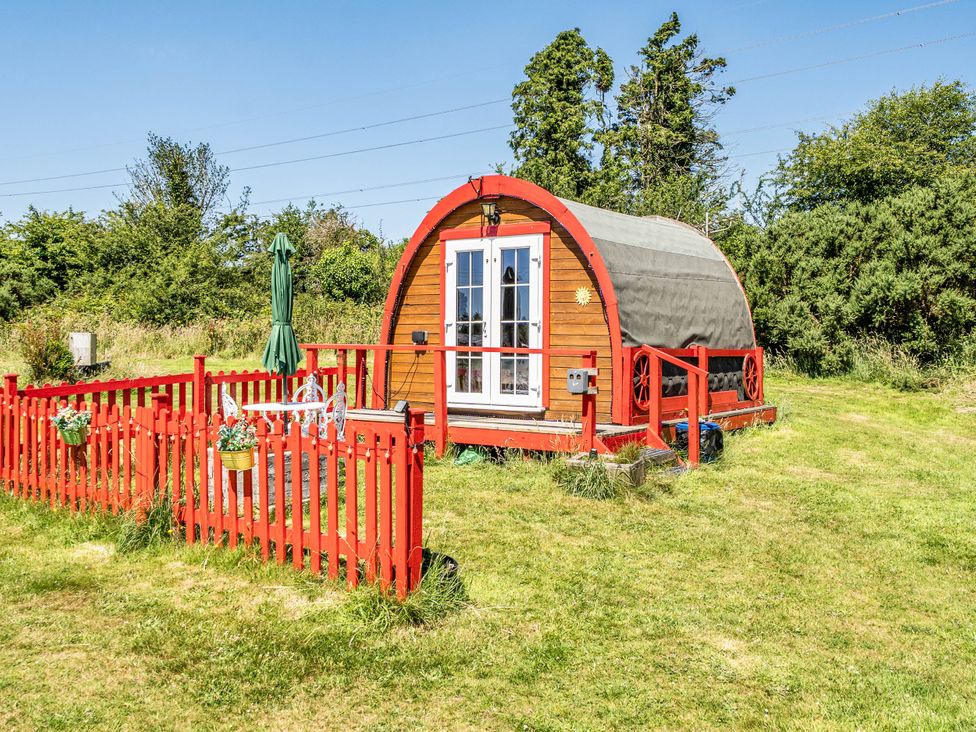 A glamping pod with a red fence and a green umbrella at St Austell Glamping in St Austell