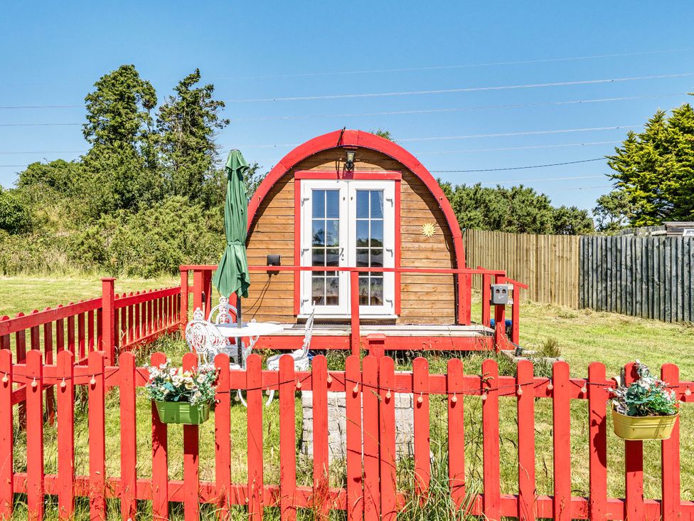 A cabin with a red fence and patio at St Austell Glamping in St Austell