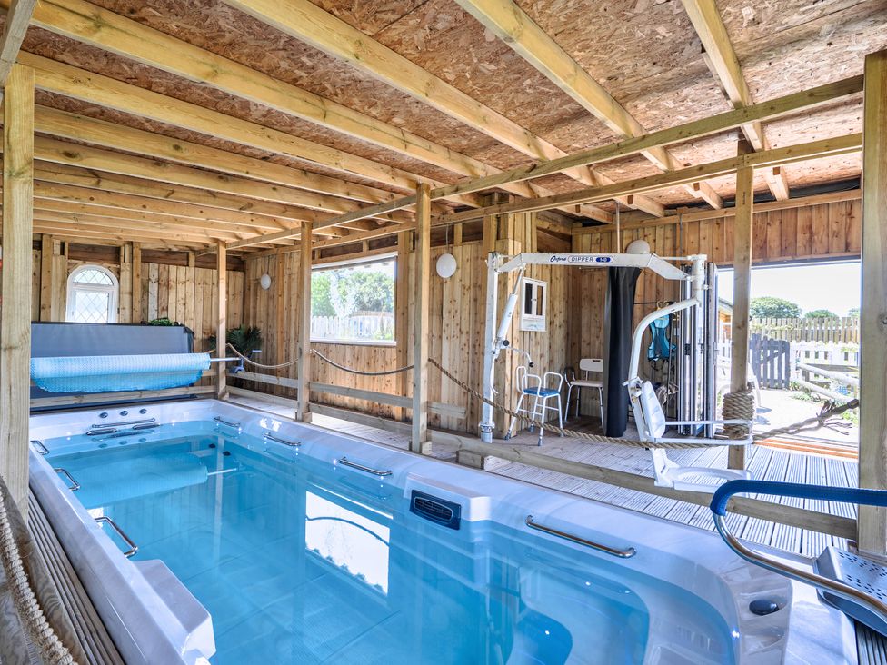 An indoor pool with exercise equipment at St Austell Glamping in St Austell