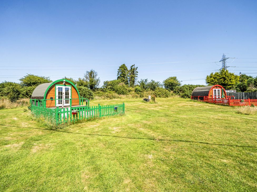 An outdoor area with green and red cabins at St Austell Glamping in St Austell