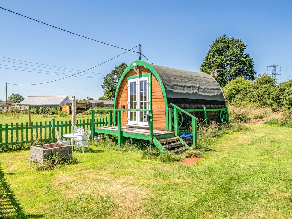 A wooden cabin with steps and a green fence at St Austell Glamping in St Austell
