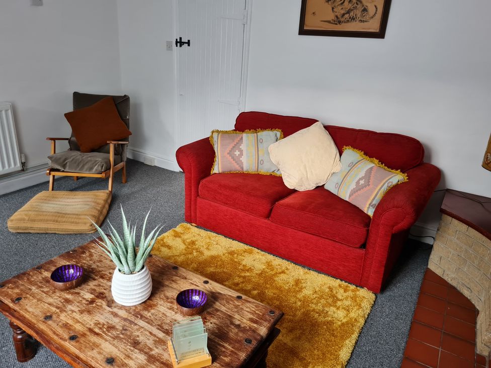 A living room with a red sofa and wooden coffee table at Charming Lincoln Cottage