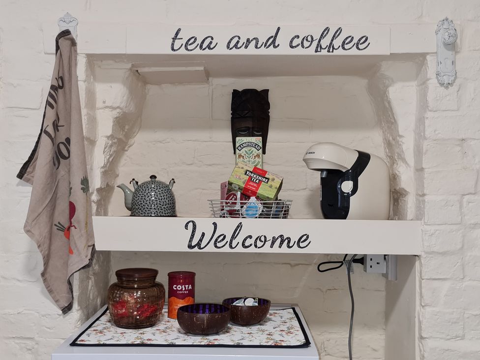 A coffee and tea station with shelves in a kitchen at Charming Lincoln Cottage