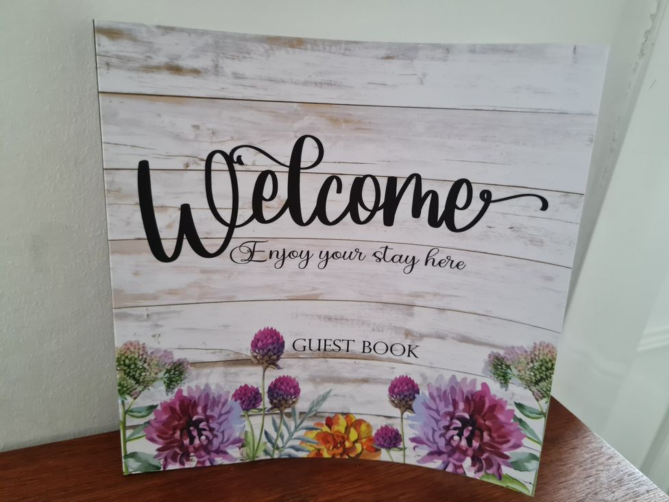 A welcome guest book with floral design on a wooden background at Charming Lincoln Cottage