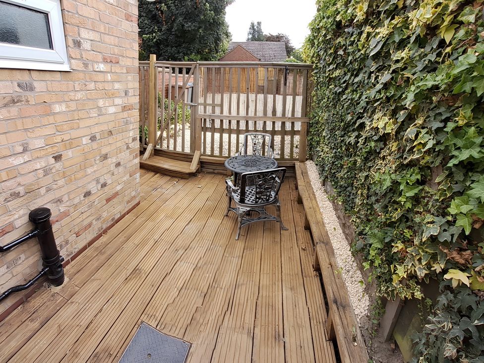An outdoor space with a table and chair on decking at Charming Lincoln Cottage