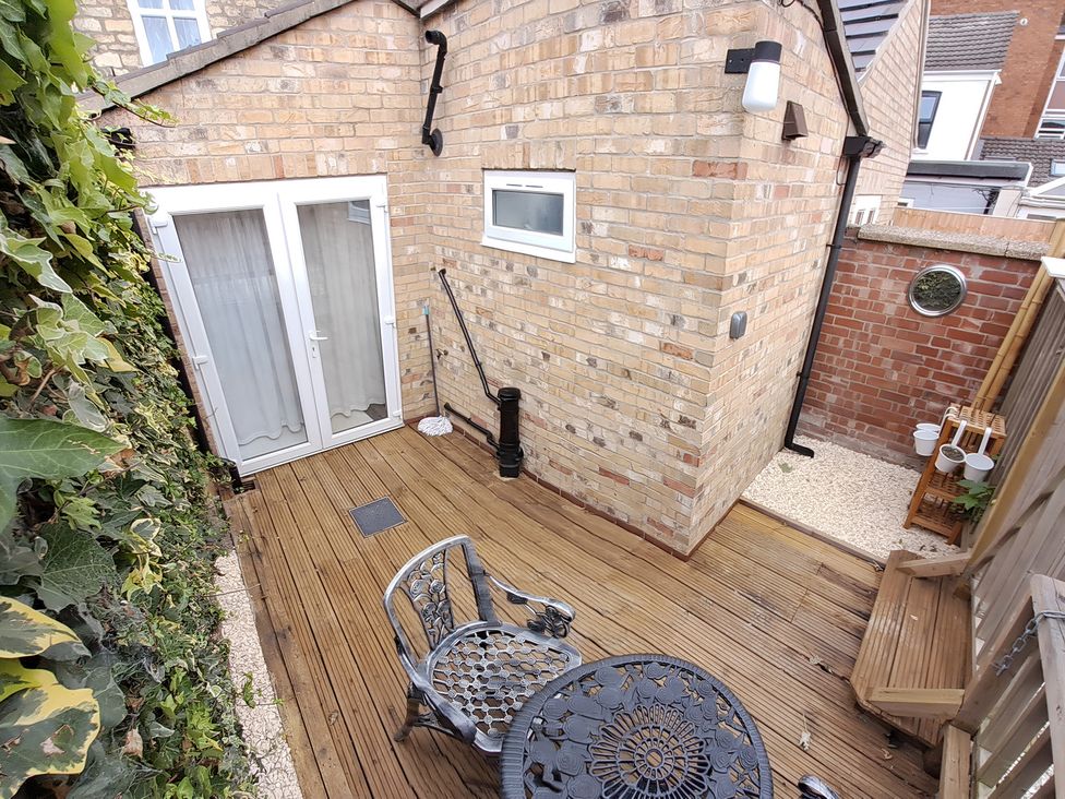 A garden area with decking, a table, and chairs at Charming Lincoln Cottage