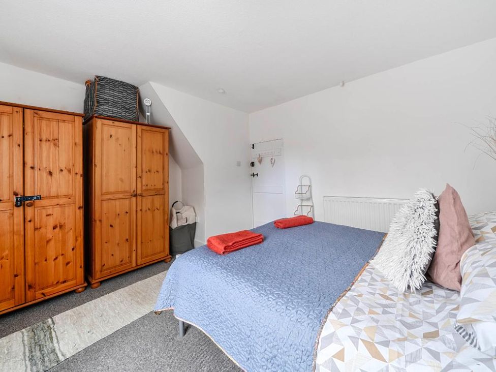A bedroom with wooden wardrobes and a bed with towels at Charming Lincoln Cottage in Lincoln