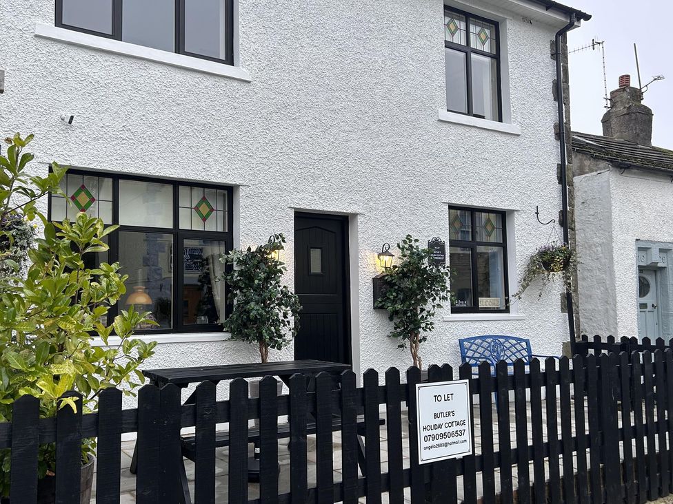 A house with a fence and furniture at Butlers Holiday Cottage in unspecified location