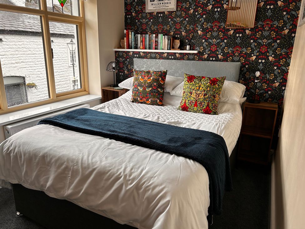 A bedroom with a bed, bedside table, and books at The Old Barn in Manchester