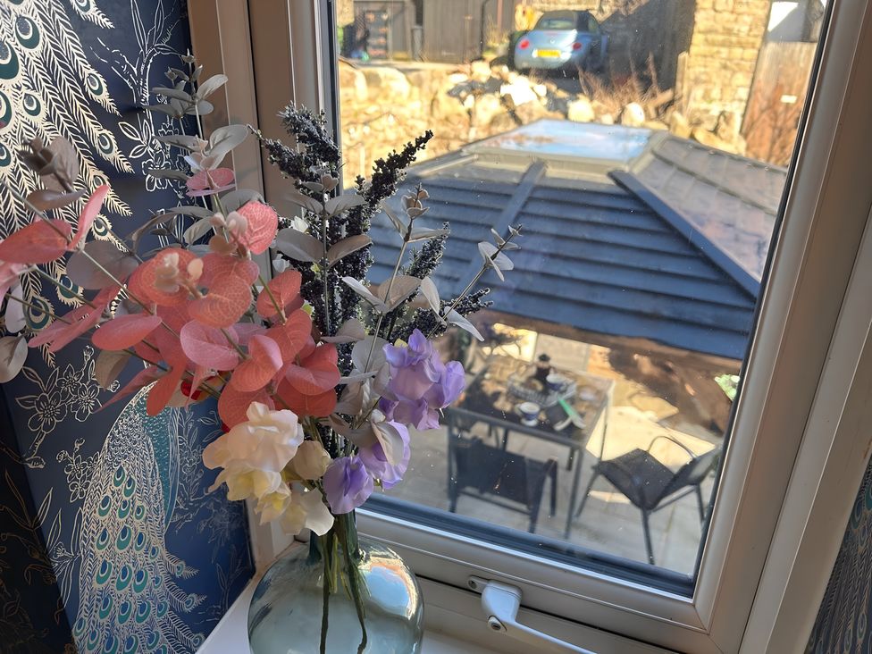 A window with artificial flowers and a view of outdoor furniture at an unknown property