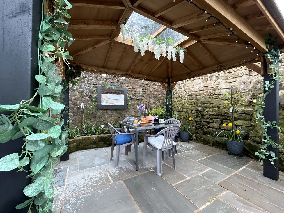 An outdoor seating area with a table and chairs under a canopy at The Old Barn in Manchester