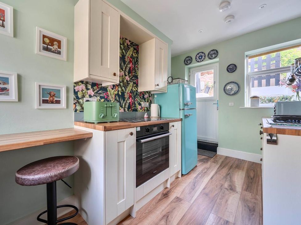A kitchen with a fridge, oven, and bar stool at 20 Main Street in Heysham