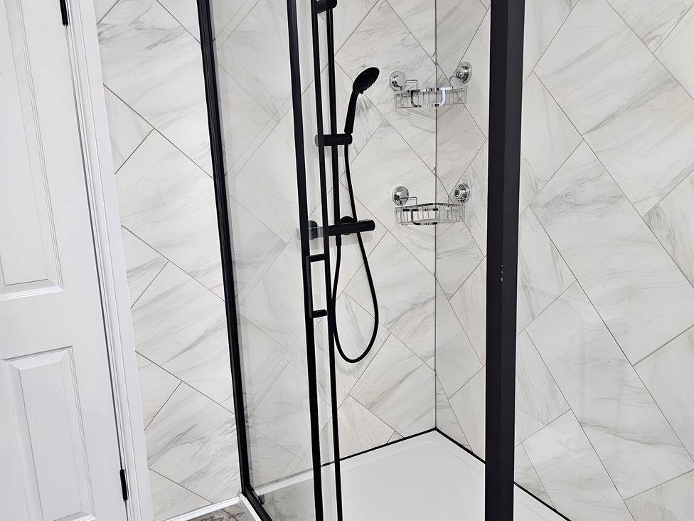 A shower with glass door and tiled walls at 140 Finchley Road