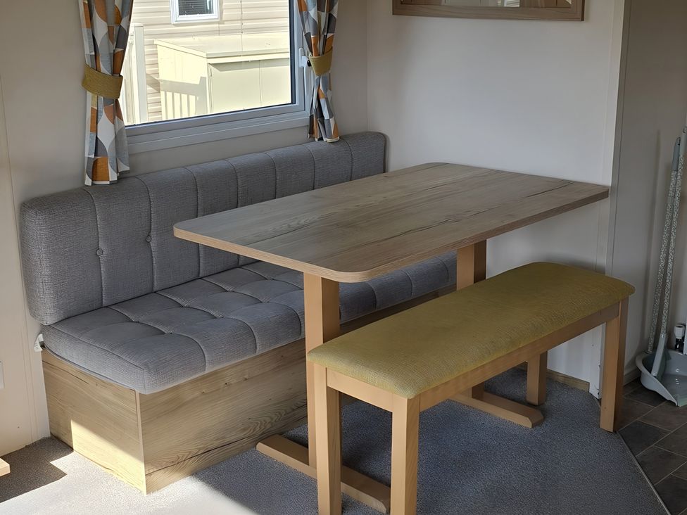 A dining area with a table and bench at Caravan