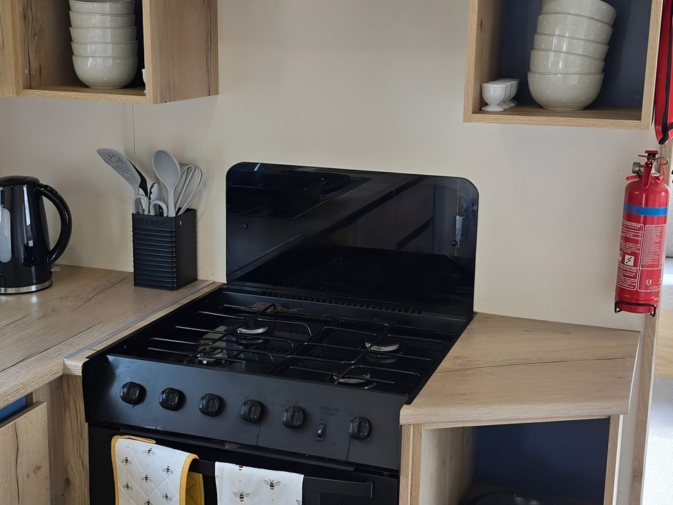 A kitchen countertop with a stove, kettle, and utensil holder at Caravan in 