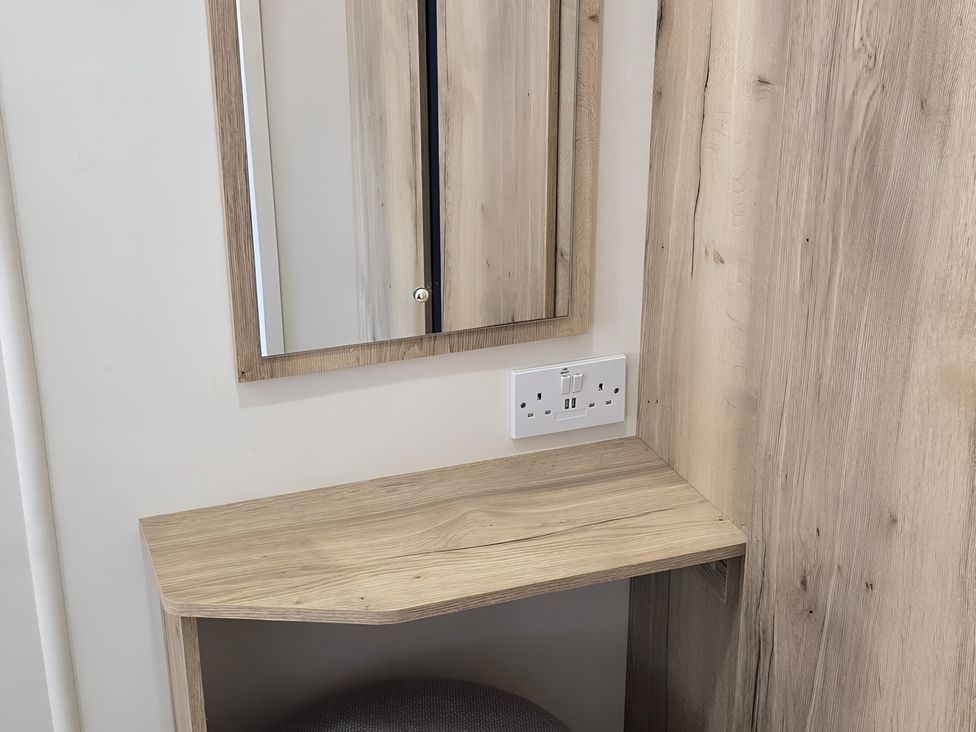 A dressing area with a mirror and a wooden shelf at Caravan