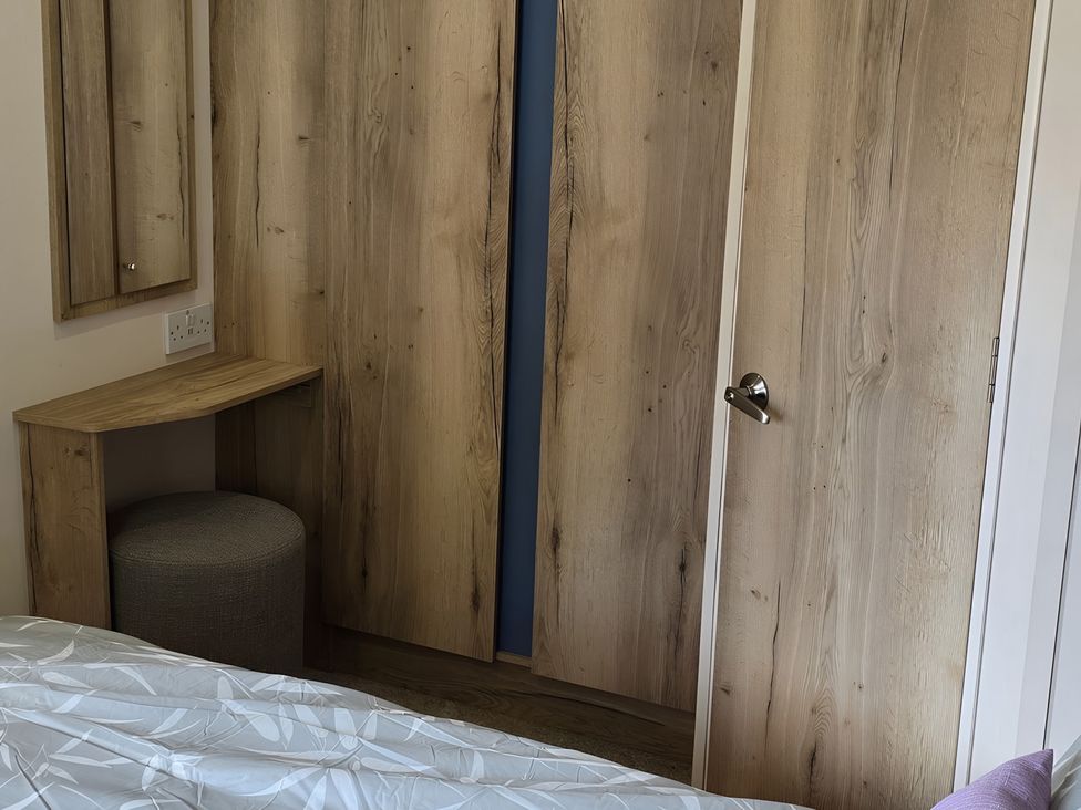 A bedroom with a wooden cabinet and mirror at Caravan