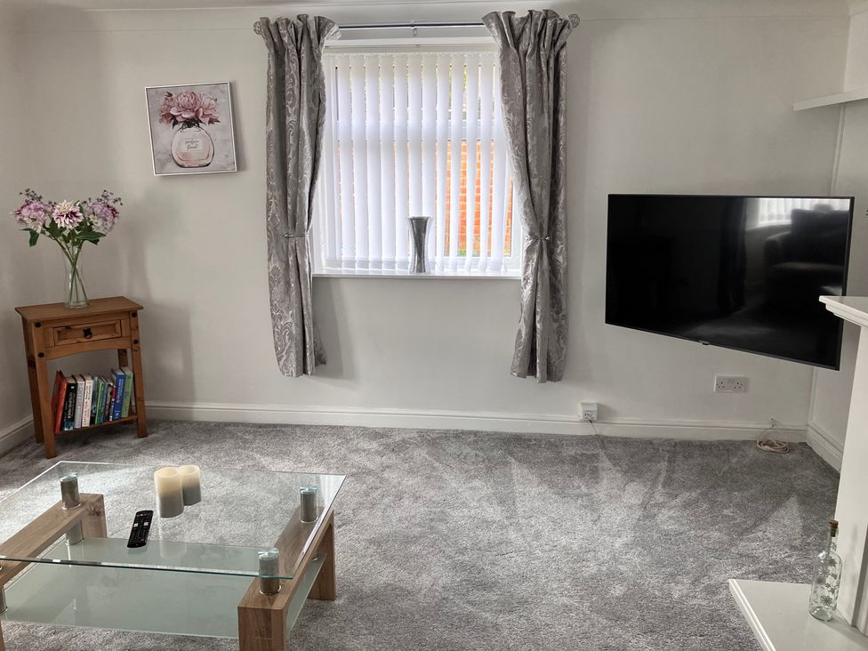 A living room with a coffee table and television at Flat 2A