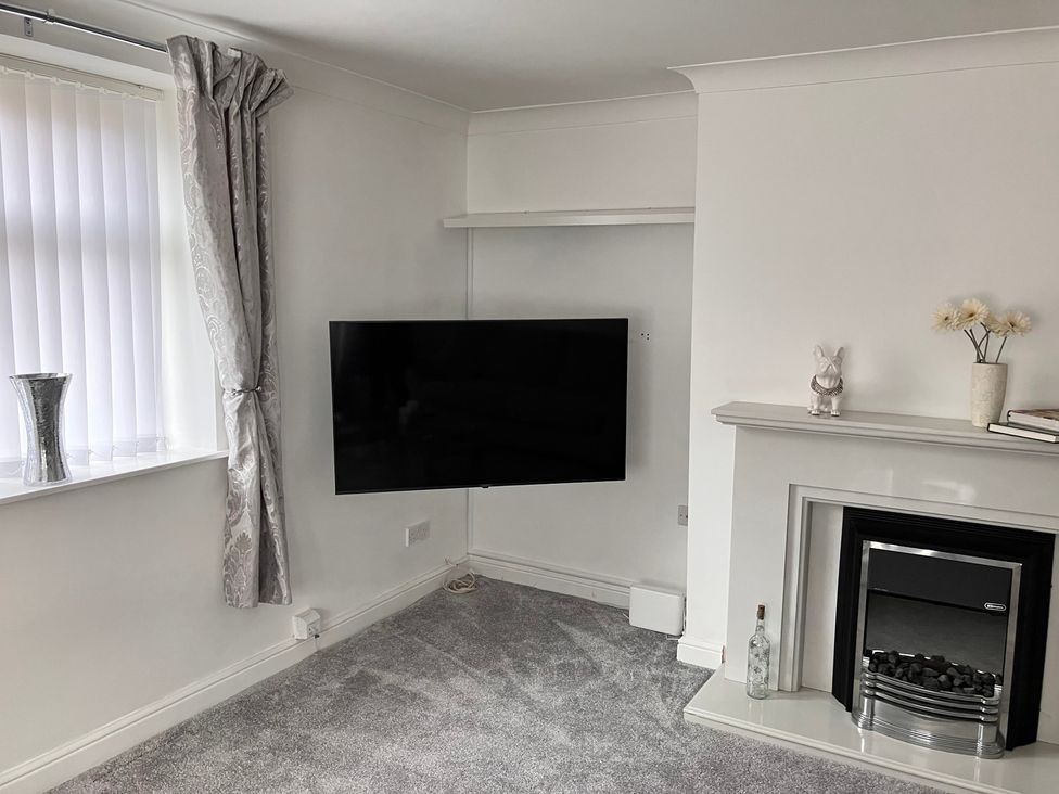 A living room with a television and fireplace at Flat 2A