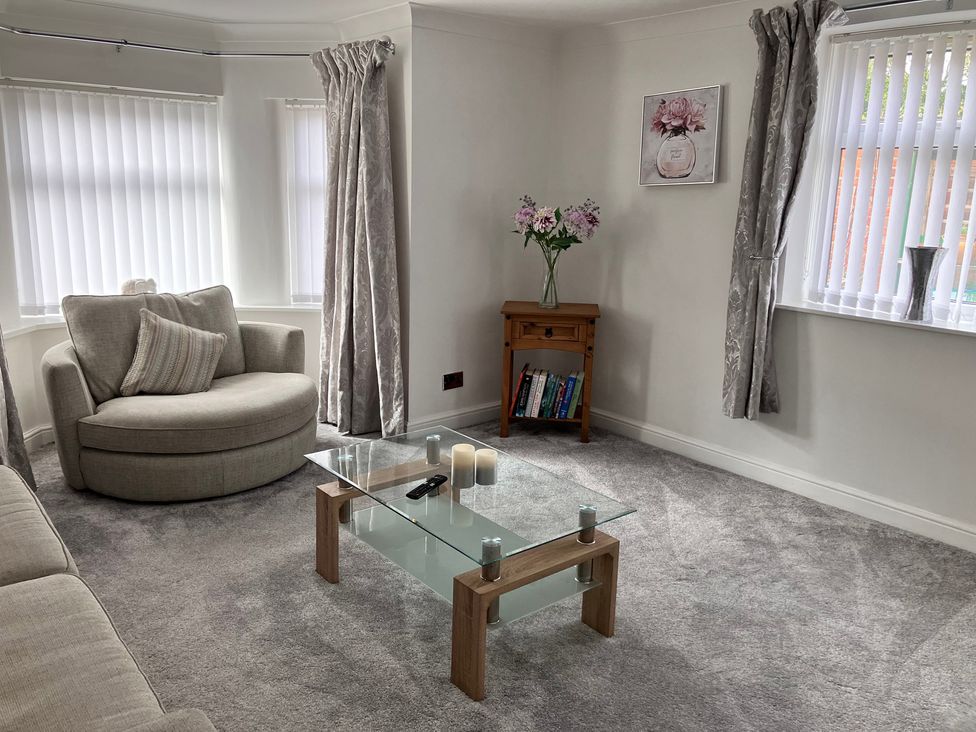 A living room with a coffee table and armchair at Flat 2A