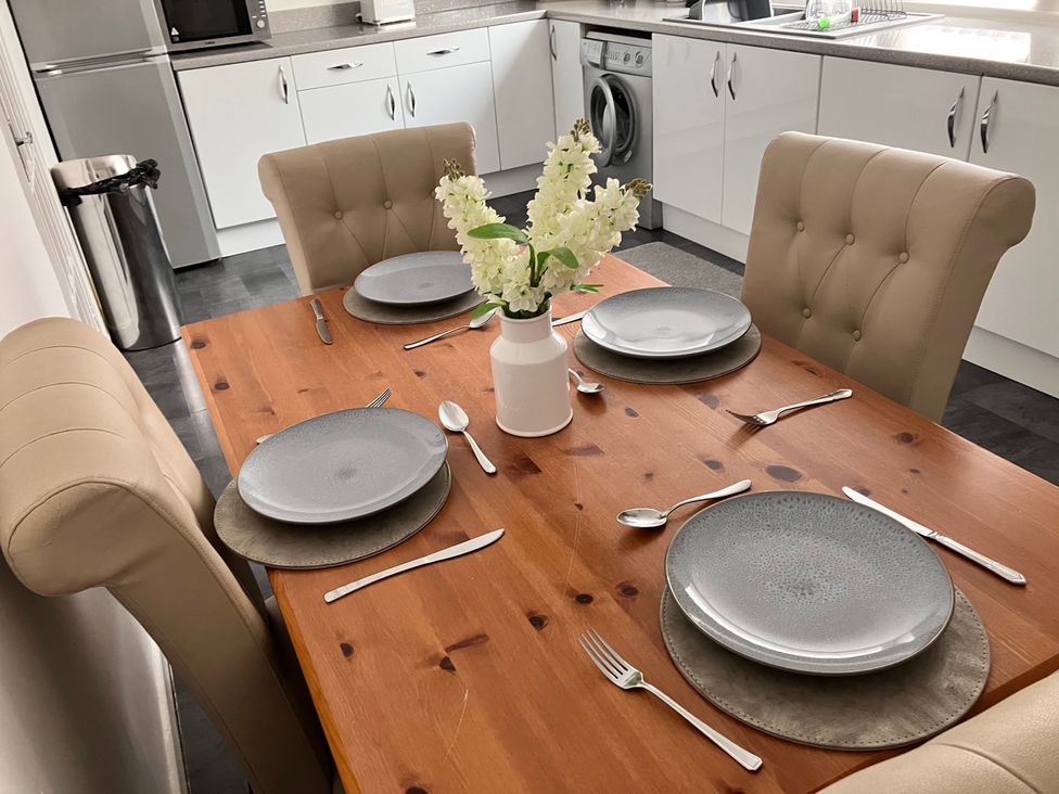 A dining table set with plates and cutlery in a kitchen at Flat 2A