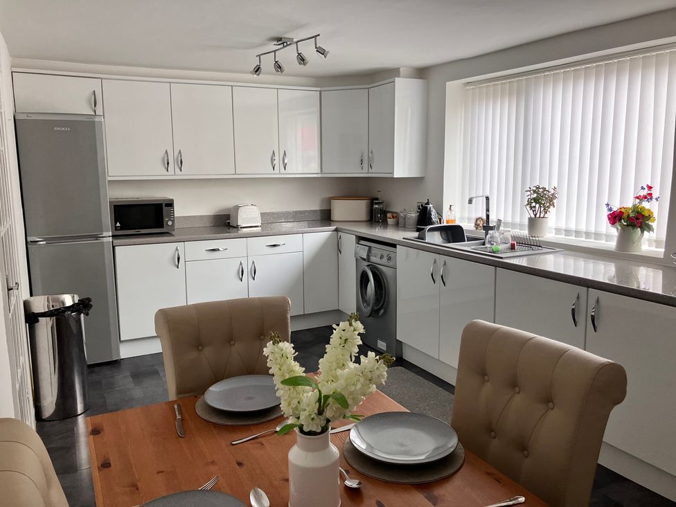 A kitchen with appliances and dining table at Flat 2A