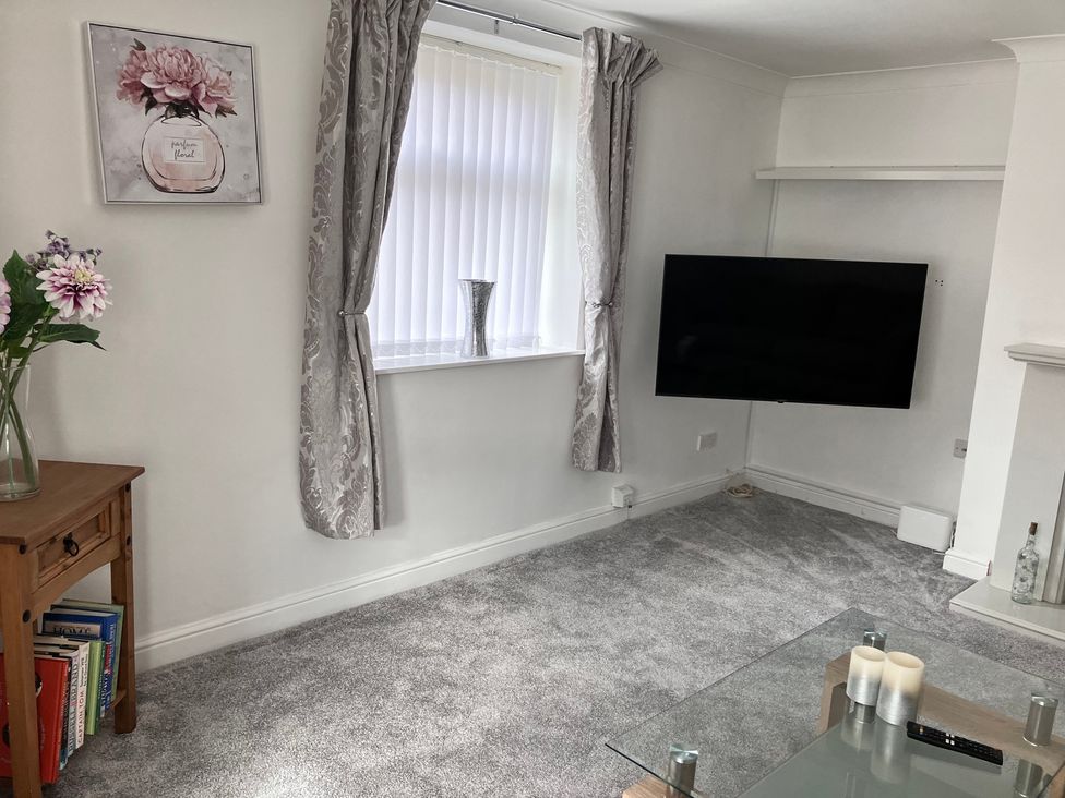 A living room with a television and a vase on a table at Flat 2A