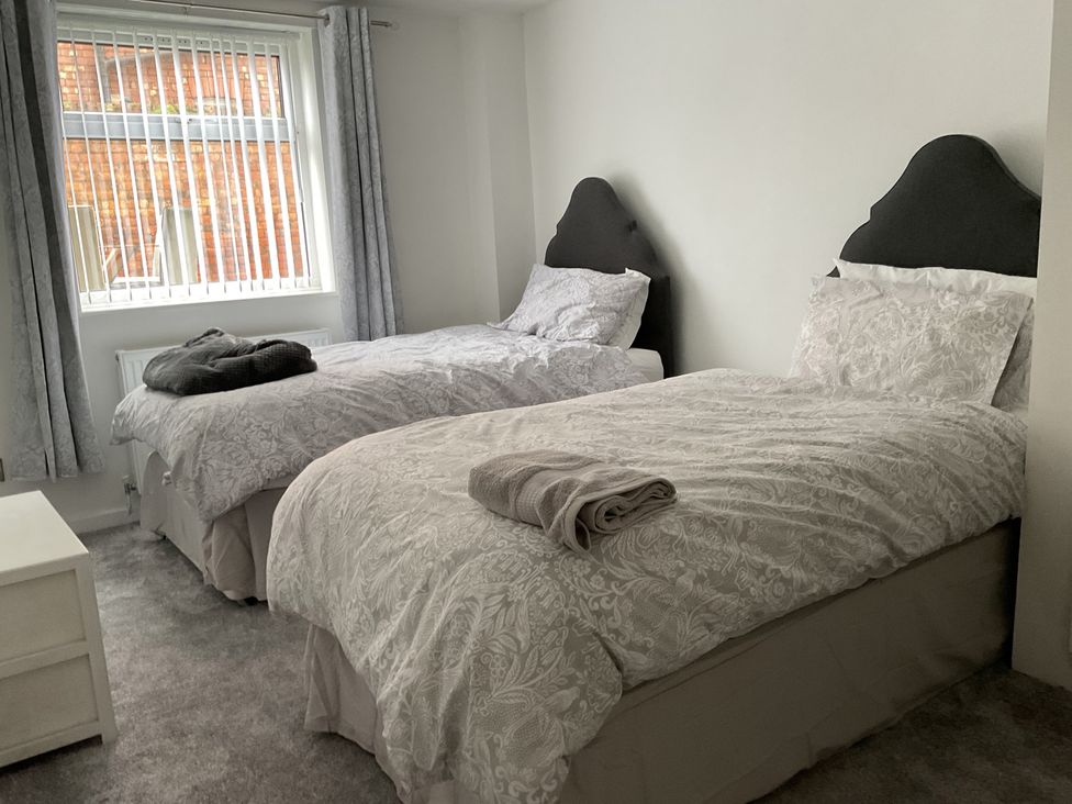 A bedroom with two beds and a bedside table at Flat 2A