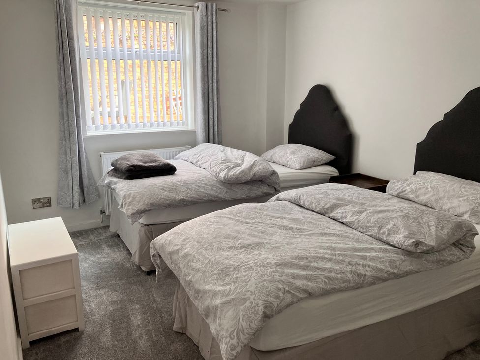 A bedroom with two beds and a window at Flat 2A 