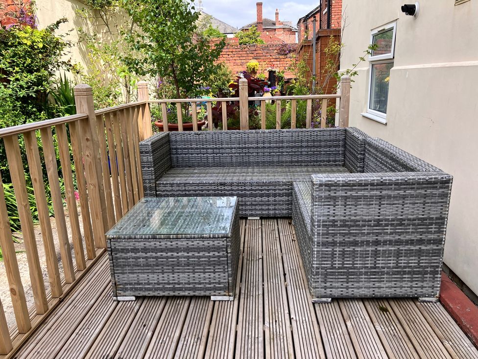 A garden with a sofa and coffee table on a wooden deck at Flat 2A