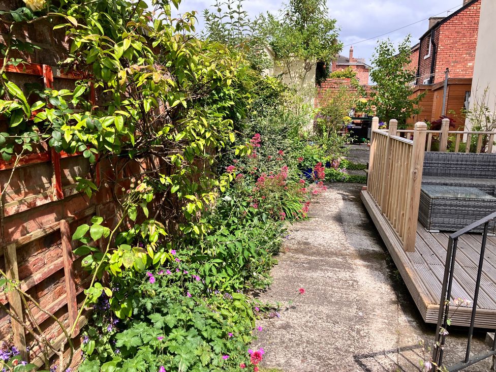 A garden with flowers and a wooden decking area at Flat 2A 